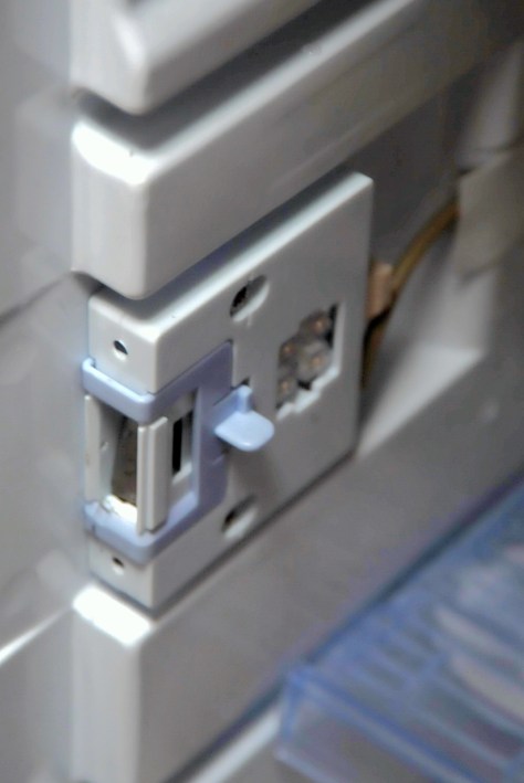 The fridge catch with the cover off. Note the unprotected wires at the back